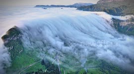 Mesmerising sea of clouds cascades down mountains in breathtaking waterfall display