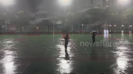 Student break dances on rain soaked sports court in China