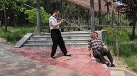 Man uses giant chopsticks to feed fruit to friend