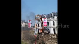 Man hula-hoops while being lifted into the air by a JCB
