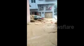 Gushing floodwater rushes down a street in China