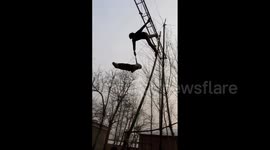 Kung fu masters perform on the top of bamboo stick held by a man