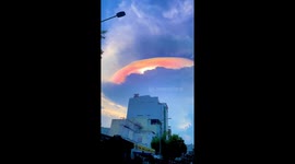 Vibrant Iridescent cloud looks like huge plant emerging form behind clouds