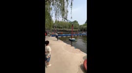 Youngsters play on awesome swing over water park lake