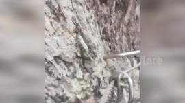 Climber hundreds of feet up shows loose screws on tourist site cliff face
