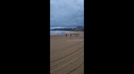 Surfers carry Olympic flame along Biarritz beach in France