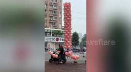 Vendor has dozens of pig balloons stacked on his motorcycle