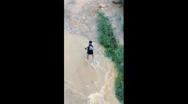 Man catches fish in flooded river in southern China
