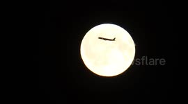 Plane is crossing the Full 'Flower Moon' that lit over city of St Petersburg, Russia