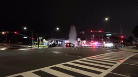 Car flipped in busy intersection at night, Fire hydrant spouting water.