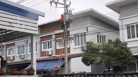 Electrical technicians carrying out repairs and maintenance on electric power cables on my street in Thailand.