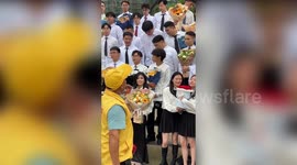 Student holds roasted duck received as gift at graduation ceremony