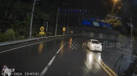 Tourist falls from scooter and slides along wet road into oncoming car