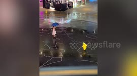 Toddler in raincoat happily splashes in puddles