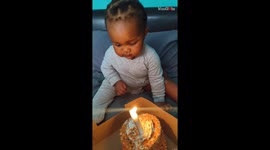 Tiny hand meets the dance of the flame on a first birthday cake
