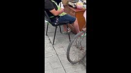 Mouse climbs onto food vendor's lap while he sleeps at stall
