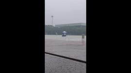 Pupils shelter under canopy to negotiate rain storm on sports field