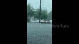 Two men paddle boat through flooded road in South Florida amid heavy rains