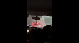 Water cascades from cliffs onto passing cars during storm