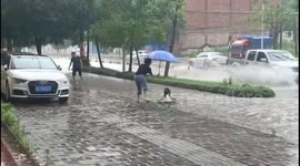 Girl sits in basin to float down flooded road in China