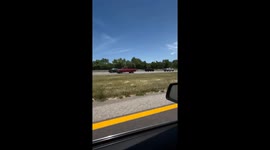Red pickup truck drives backwards at full speed on freeway
