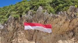 Raising a giant flag at the cliff beach of Aceh Besar, Indonesia