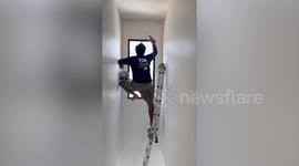 Gymnast-like painter stretches into awkward positions while decorating tall walls