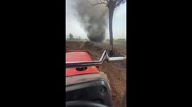 Huge dust devil tornado tears up field while farmer rides tractor