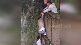 Firemen rescue walker clinging to river wall in China