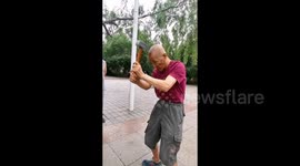 Elderly man's unique workout with traditional oil extraction hammer sparks debate in China