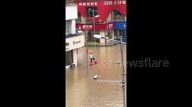 Chinese man's creative solution to navigate flooded street on stools ends in soaking fall