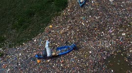 Indonesia: Residents using a wooden boat clean up plastic waste that has settled in the Citarum River in Batujajar, West Bandung Regency