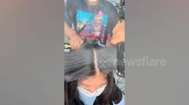 Hairstylists simultaneously straight client's hair