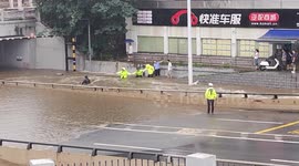 Traffic police brave rapid flood to rescue trapped scooterer in southern China