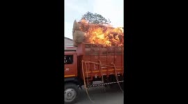 Truck carrying bales of burning straw hurtles down street
