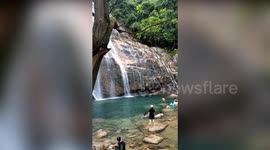 Tourist narrowly avoids large rocks as he slides down waterfall