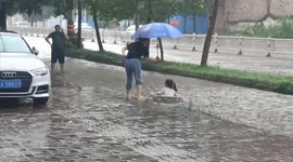 Little girl drifts down flooded road in makeshift boat