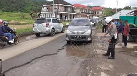 Vehicles plunge into hidden potholes on flooded road in Indonesia, guided by police