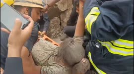 Officials rescue a woman stuck in rubble after a building collapsed in Surat’s Pali village