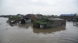 India: A settlement partially submerged in floodwater stands in Darang