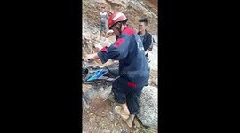 People struggled to move their motorbikes and belongings across the bridge that was completely destroyed after the flash flood