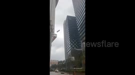 High-rise crane basket loses control in strong rainstorm, shattering building glass