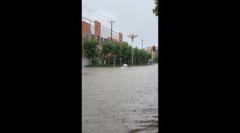 Father uses plastic tub to float children along flooded road