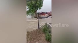 Villager shimmies across iron pipe above raging floods to reach safety