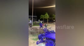 Man carries chairs against strong winds outside beachside restaurant in Malaysia