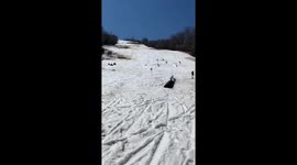 Snowboarder flips over blue barrels and lands on his back