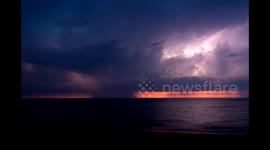 Spectacular lightning flashes against a vivid sunset over Lake Erie in 4K time lapse