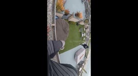 two guys stand on ledge, one jumps into pool from 5 stories up, other one stays on the ledge