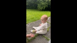Baby tries to throw a ball for the dog with dad's assistance