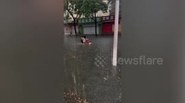 Girls ride electric scooter through flooded road in China